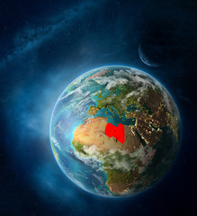Libya from space on Earth surrounded by space with Moon and Milky Way. Detailed planet surface with city lights and clouds.
