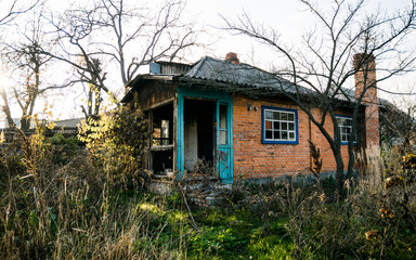 Fototapeta na wymiar Old abandoned brick house among the autumn old garden