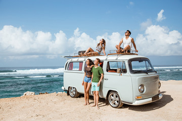 Hipster girl relaxing with friends on the retro van roof © Odua Images