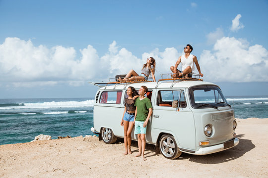 Hipster girl relaxing with friends on the retro van roof - Powered by Adobe