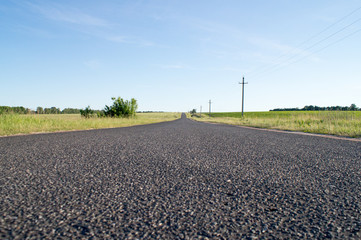 The empty asphalted road going to the blue sky