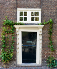 Fototapeta na wymiar Old black wooden door with white frame on brown brick wall.