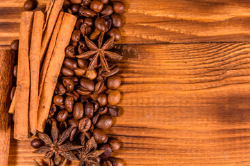 Pile of the coffee beans, star anise and cinnamon sticks on wooden table. Top view