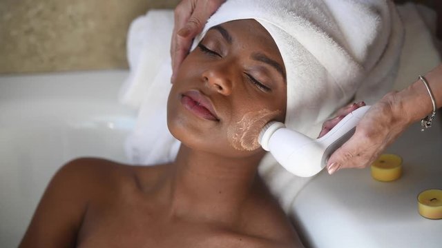 African-American woman applying cream on her face in a spa