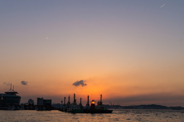Fototapeta premium 岸壁の灯台に沈む夕日と広がる空