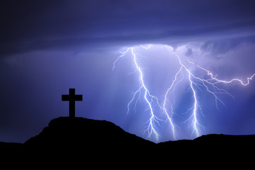 Silhouette of a cross on the mountain with rays and bad weather