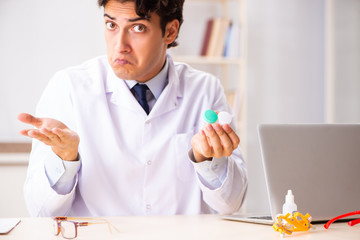 Young handsome doctor ophthalmologist with contact lenses in hos