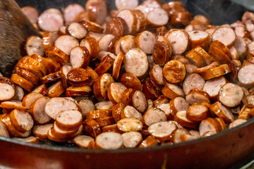 Obraz premium Detailed Closup Photo of Sliced Sausages Being Baked on Frying Pan