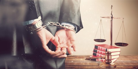 Cropped image of male hands in handcuffs behind his back