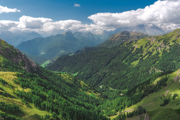 Naklejka premium Green grass and blue sky with clouds around high mountains, Dolomites in Italy.