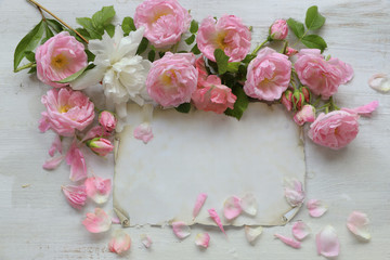 Roses with paper on wooden background 