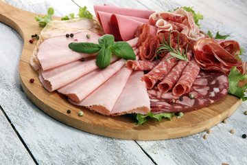 Food tray with delicious salami, pieces of sliced ham, sausage and salad. Meat platter with selection.