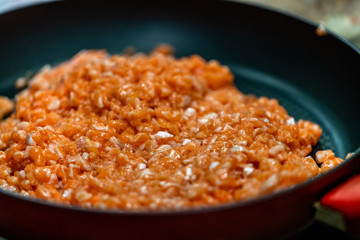 Red Pan with Pile of Cutted Salmon Pieces in the Foreground, Male Chef Cutting Fresh Salmon on the Wooden Board in the Background