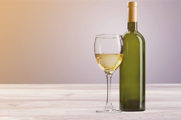 Glass and bottle of white wine on grunge background