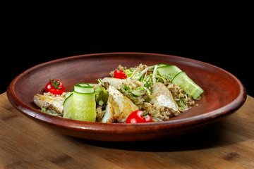 Fish with fresh green leaves salad and quinoa. The plate occupies the entire frame.