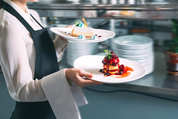 Waiter serving in motion on duty in restaurant long exposure. The waiter carries dishes.