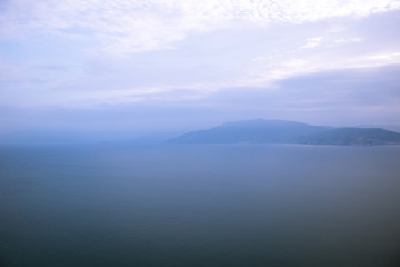 Fototapeta na wymiar wallpaper soft nature scenery landscape of morning foggy mountain silhouette near sea bay calm water surface