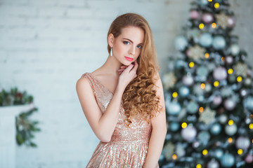 Holidays, celebration and people concept - young woman in elegant dress over christmas interior background