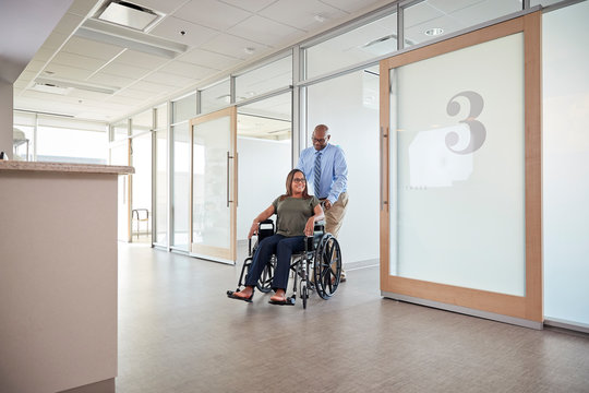 Man pushing woman in wheelchair