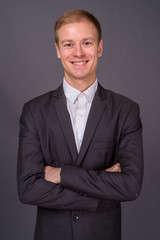 Portrait of young handsome businessman against gray background