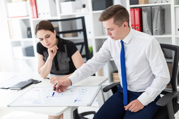 Obraz premium Young people in the office discussing the schedule on a magnetic Board.