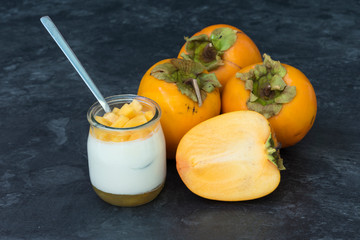 Yogur con caqui y la fruta sobre la mesa