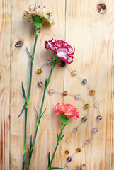 Murano glass beads and a bouquet of carnations on a wooden table. Composition with flowers and handmade jewelry.