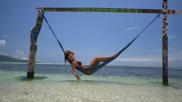 Beautiful shot of woman lying down on hammock in crystal water of the ocean, paradise vacation concept