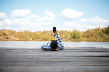Image of brunet with smartphone in hands of day