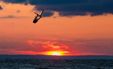 Jumping kitesurfer with a dramatic sunset in the background