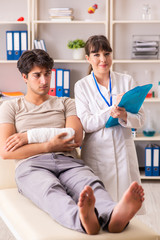 Young man with bandaged arm visiting female doctor traumatologis