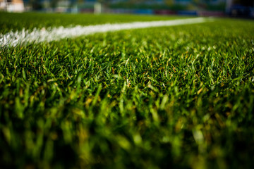 Green bright colorful grass pitch of football stafium, close up with beautiful bokeh and stripes