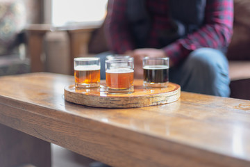 Man in plaid shirt sampling beer from a flight