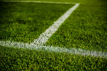 Green bright colorful grass pitch of football stafium, close up with beautiful bokeh and stripes