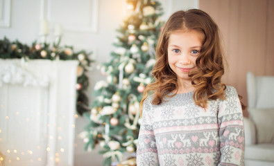 Merry Christmas and Happy New Year. Beautiful, little girl in New Year's environment. A child in a knitted sweater and knitted boots.