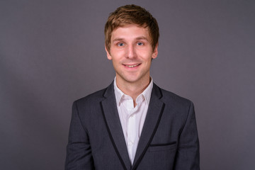 Portrait of young handsome businessman against gray background