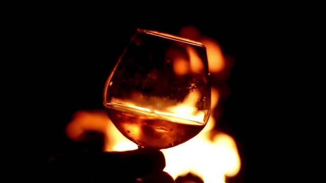 Brandy glass with fire background swirling drink with ice