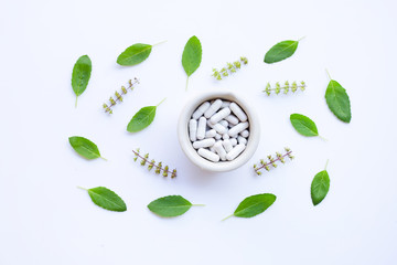 Flower of holy basil and leaves with herbal medicinecapsules pills on white background