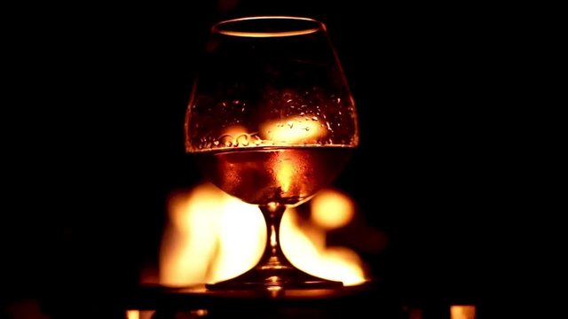 Pick up brandy glass with fire in the background 