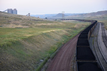 Long coal train winding through loading silos, open pit coal mining in the Powder River Basin.