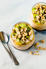Vegan layered banana dessert of green buckwheat, chia seeds and quinoa with blueberry jam in a glass with fresh fruits, nuts and honey. healthy morning meal for breakfast.