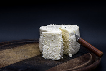 Brazilian minas white cheese on a wooden cutting board isolated in dark background