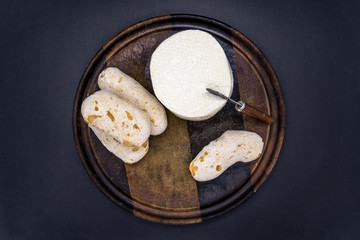 Cheese bread and brazilian minas white cheese on a wooden cutting board isolated in dark background