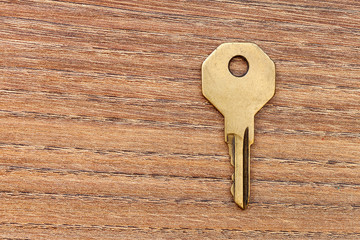 Conceptual background of a door key on a wooden table top view with copy space for text.
