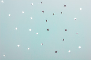 Minimalist mint color background with metallic star shaped confetti. Holiday decoration concept. Christmas and New Year.