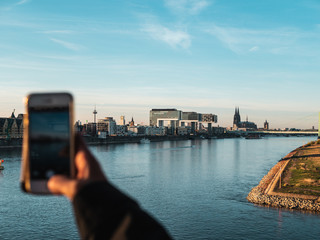 Young Woman taking pictures of Cologne with her smartphone