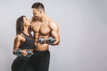 Fototapeta na wymiar Athletic man and woman with a dumbells isolated over white background. Personal fitness instructor. Personal training.