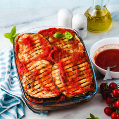 Vegan Eggplant Parmigiana made of peas and lentils and fresh tomatoes on a marble kitchen table. Healthy comfort recipe for the whole family