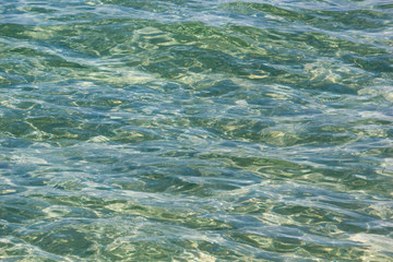 Transparent sea water surface in the rays of the summer sun, background, texture