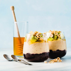 Vegan layered banana dessert of green buckwheat, chia seeds and quinoa with blueberry jam in a glass with fresh fruits, nuts and honey. healthy morning meal for breakfast.